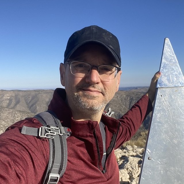 Cassidy Lackey at a mountain summit marker